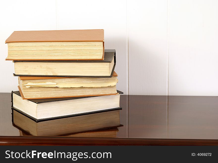 Old hardback books on polished dark cherry wood table. Old hardback books on polished dark cherry wood table