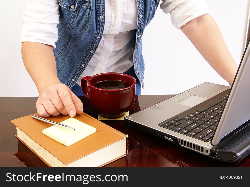 Woman's torso leaning over a laptop on desk with book, pen, paper, and coffee. Woman's torso leaning over a laptop on desk with book, pen, paper, and coffee.