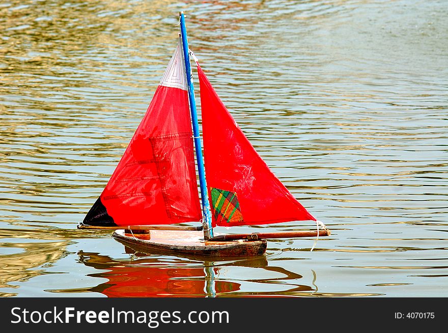 France, Paris: green water yellow leaves and a little toy boat with red sail. France, Paris: green water yellow leaves and a little toy boat with red sail