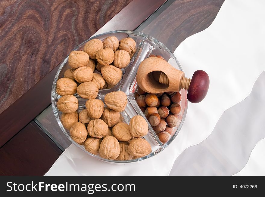 Walnuts and hazelnuts on table in glass utensil. Walnuts and hazelnuts on table in glass utensil