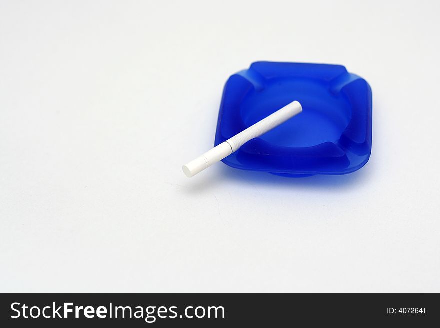 White cigarette on blue ashtray with white background. White cigarette on blue ashtray with white background