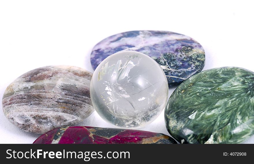 A structured crystal sphere surrounded with colored stones as an egg in a nest, on white. A structured crystal sphere surrounded with colored stones as an egg in a nest, on white