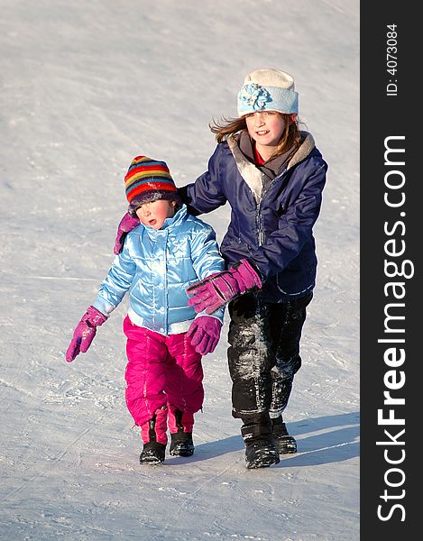 Several children sledding on a hill in the winter