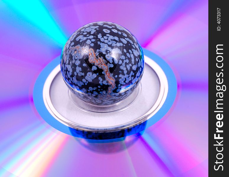 Small painted stone ball on a compact disk surface with a rainbow effect. Small painted stone ball on a compact disk surface with a rainbow effect