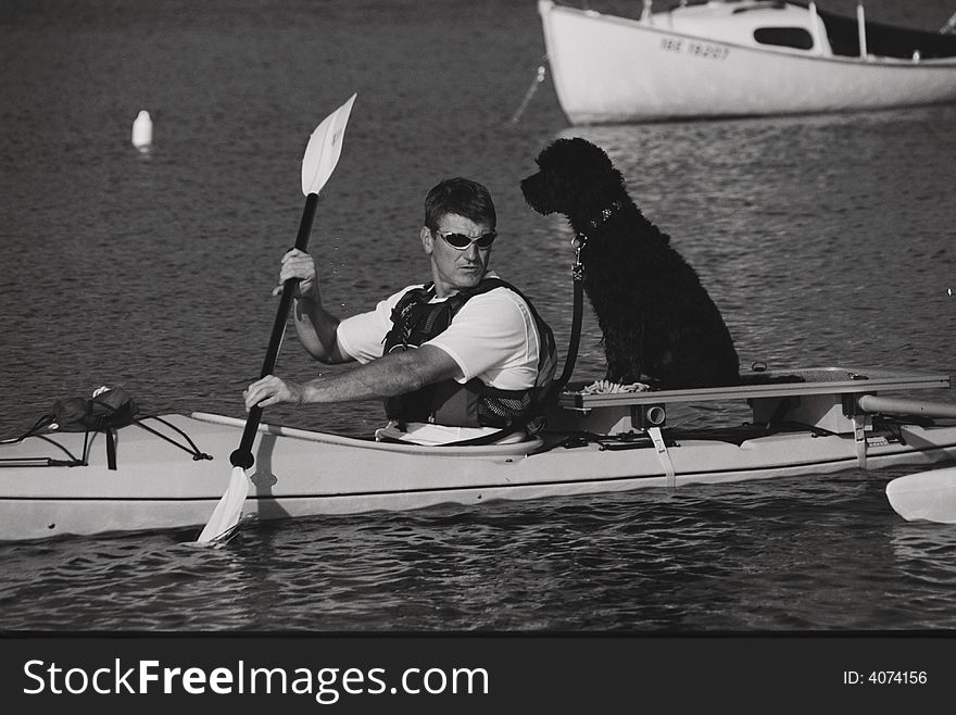 Portuguese Water Dog and crew mate kayaking the shores of Georgian Bay, Ontario on a special outrigger designed for added carrying capacity