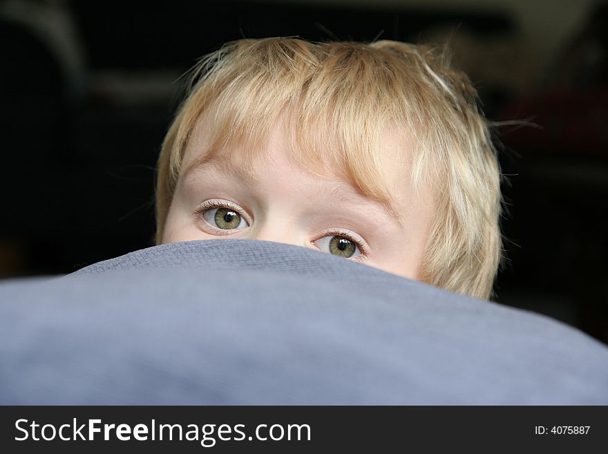 A partially obscured face of a child emerging from hiding. A partially obscured face of a child emerging from hiding