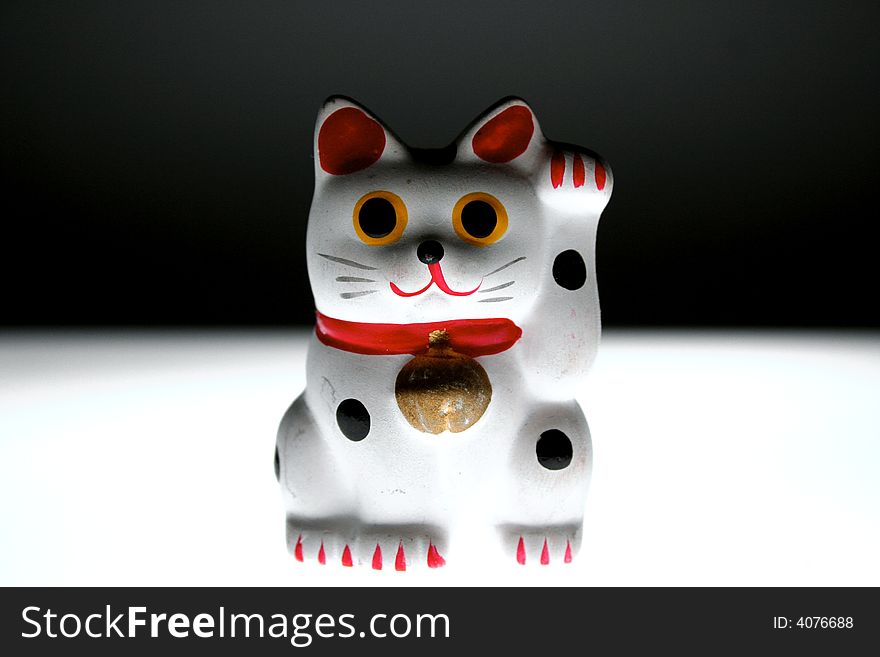 Asian good luck cat (Maneki Neko) which is believed to bring good luck and money.(on a black and white background). Asian good luck cat (Maneki Neko) which is believed to bring good luck and money.(on a black and white background)