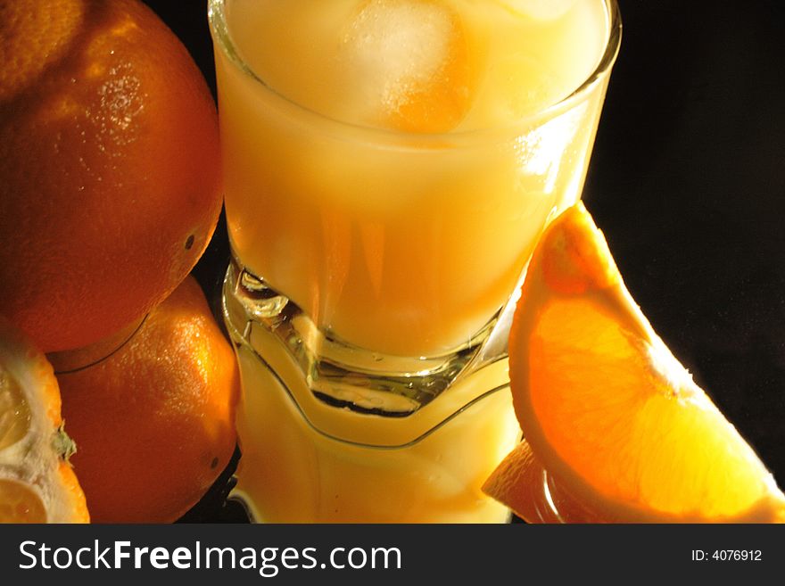 Slit orange and glass of orange juice with ice on dark. Slit orange and glass of orange juice with ice on dark