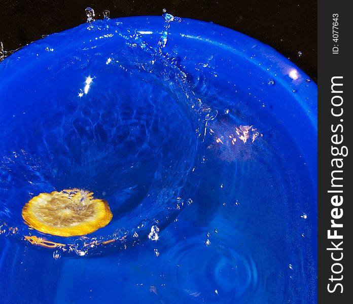 Citrus fruit slice fallen in water and a crown of water from its falling