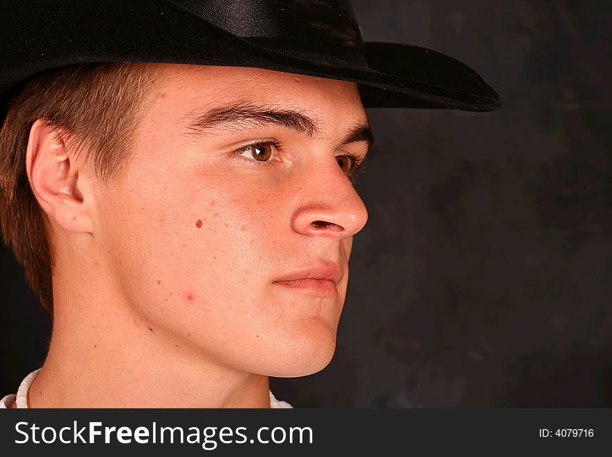 Close Up of young male model in cowboy hat on a black background.