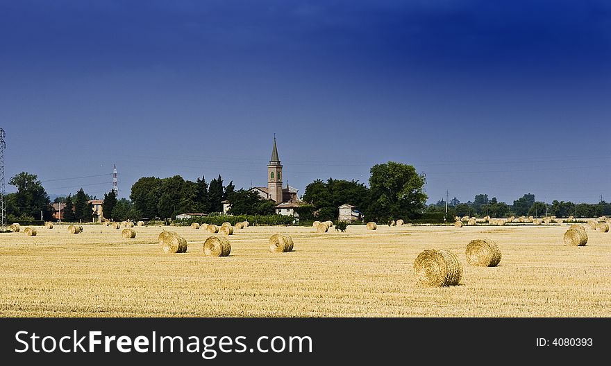 View of a wheat field after harvest in Piedmont, Italy. Village and church in background. View of a wheat field after harvest in Piedmont, Italy. Village and church in background.