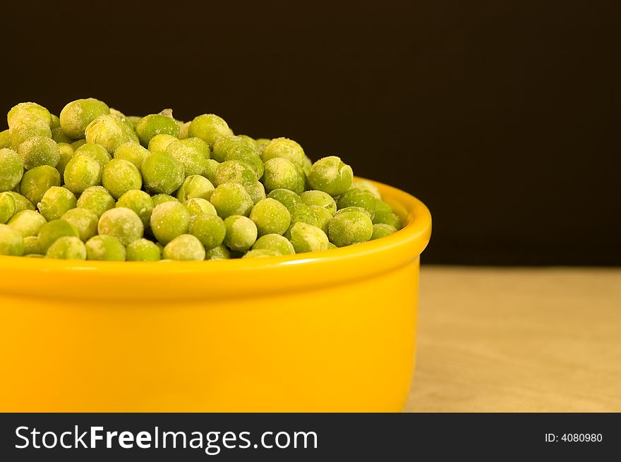 A closeup view of a yellow bowl of 
frozen green peas ready to be cooked and eaten. A closeup view of a yellow bowl of 
frozen green peas ready to be cooked and eaten.