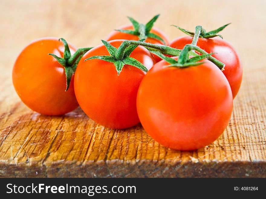 Five tomatoes on the vine on a wooden block
