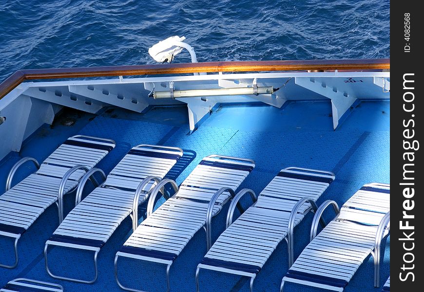 Lounge chairs in a row on a ships deck. Lounge chairs in a row on a ships deck.