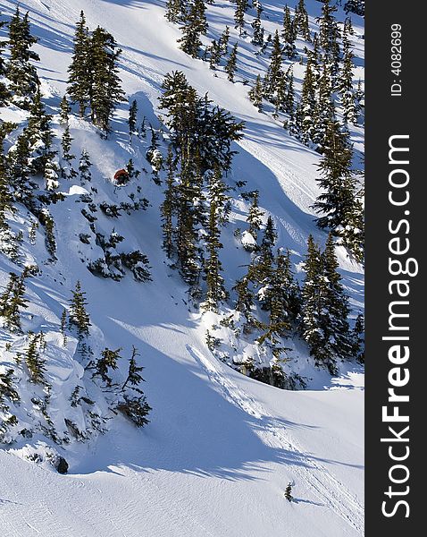 A snowboard athlete drops off a large cliff into deep powder snow. A snowboard athlete drops off a large cliff into deep powder snow.