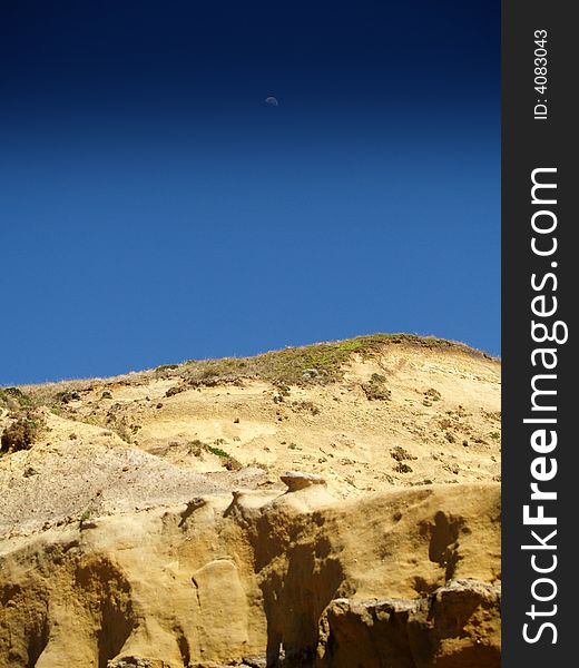 A high contrast rock, with deep sky colors.  The moon can also be seen in the sky. A high contrast rock, with deep sky colors.  The moon can also be seen in the sky.