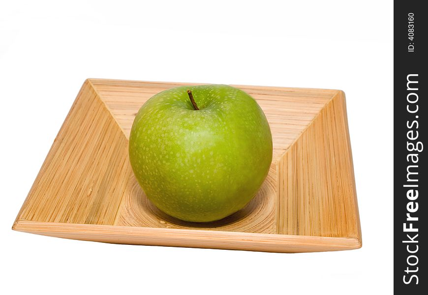 Still-life with fresh green apple on the pressed bamboo dish isolated on white