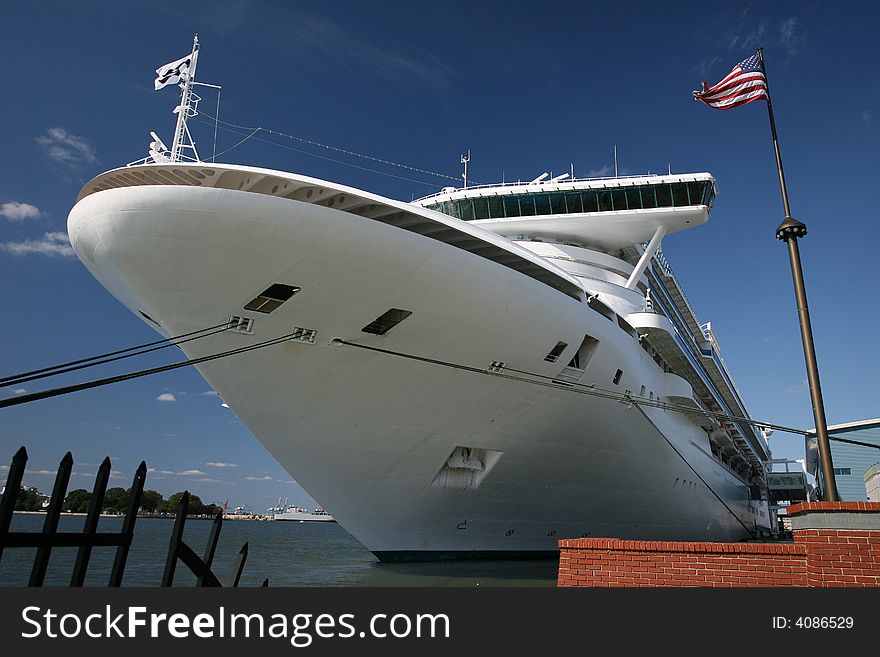 Large cruise ship in port with blue sky and American Flag.