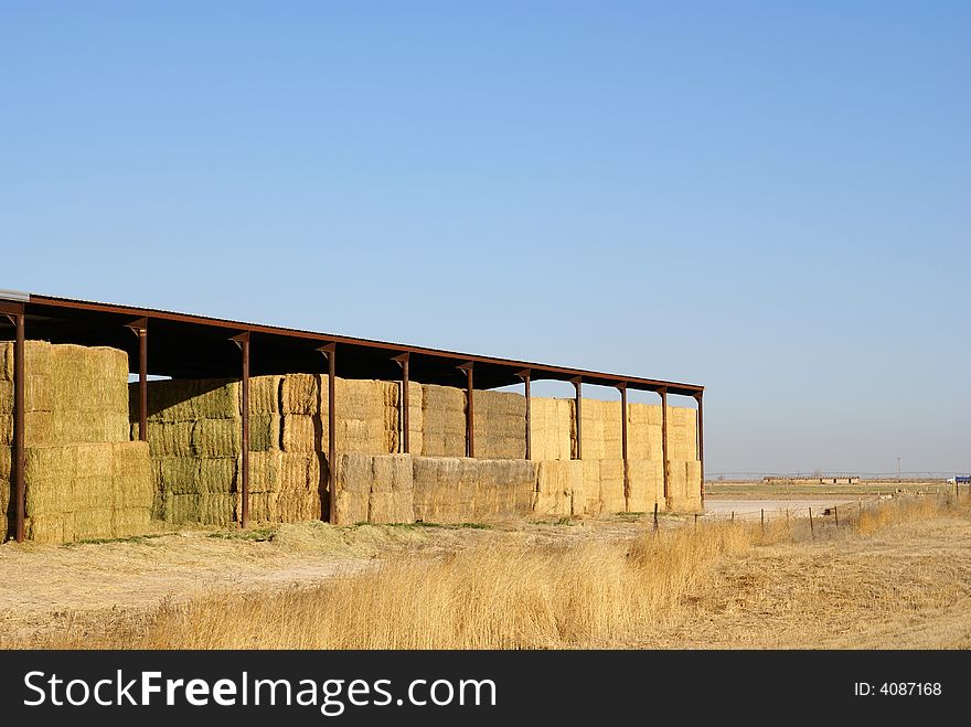 Stacked bales of sheltered hay under a deep blue sky. Stacked bales of sheltered hay under a deep blue sky