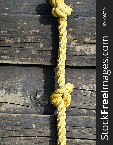 A yellow rope up against wooden planks, this is part of a children's jungle gym.