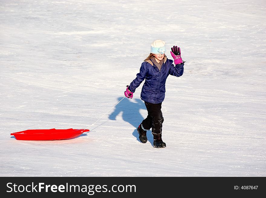 One little girl sledding on a winter day in a red sled