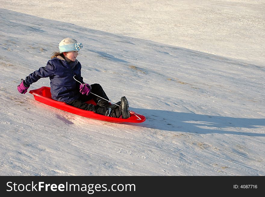 One little girl sledding on a winter day in a red sled