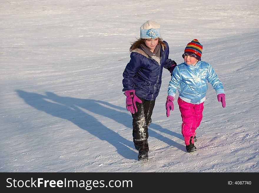 Several children sledding on a hill in the winter