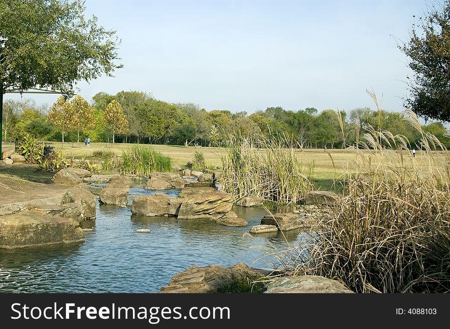A refeshing pond accented with large boulders in the middle of a large park. A refeshing pond accented with large boulders in the middle of a large park.