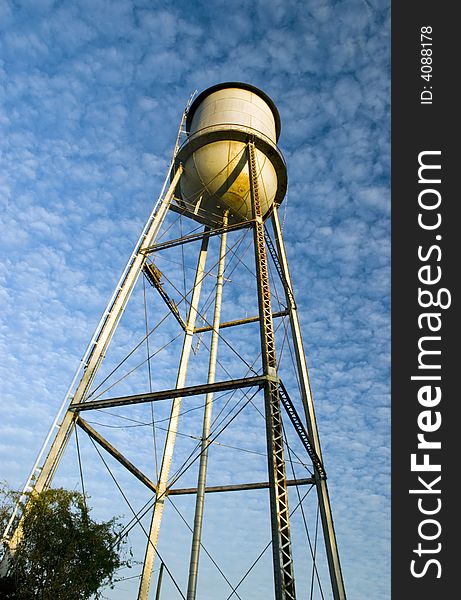 An old water tower framed against a beautiful blue sky filled with white puffy clouds.