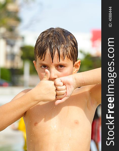 Boy wet in pool displaying a thumbs up and a thumbs down. Boy wet in pool displaying a thumbs up and a thumbs down.