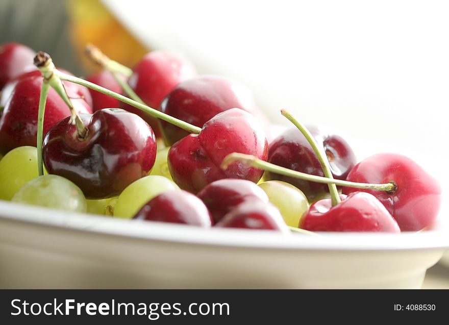 Bowl of Cherry and grape fruits on white. Bowl of Cherry and grape fruits on white
