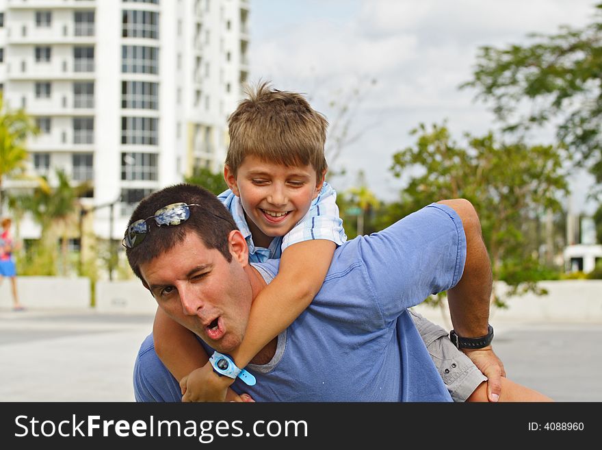 Boy Holding on to a guy. Both Smiling and making funny faces