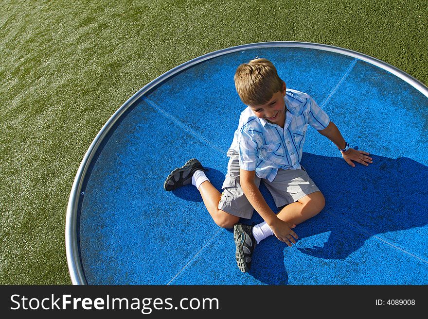 Boy spinning on a turn table in the park. Boy spinning on a turn table in the park