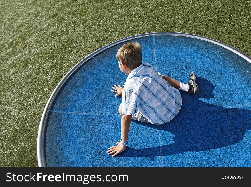 Boy spinning on a turn table in the park. Boy spinning on a turn table in the park