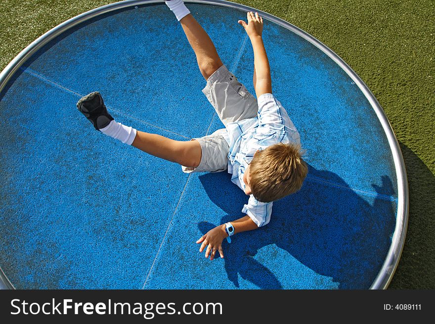 Boy spinning on a turn table in the park. Boy spinning on a turn table in the park