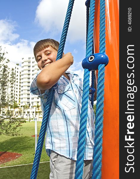 Kid holding on to blue ropes and smiling. Kid holding on to blue ropes and smiling
