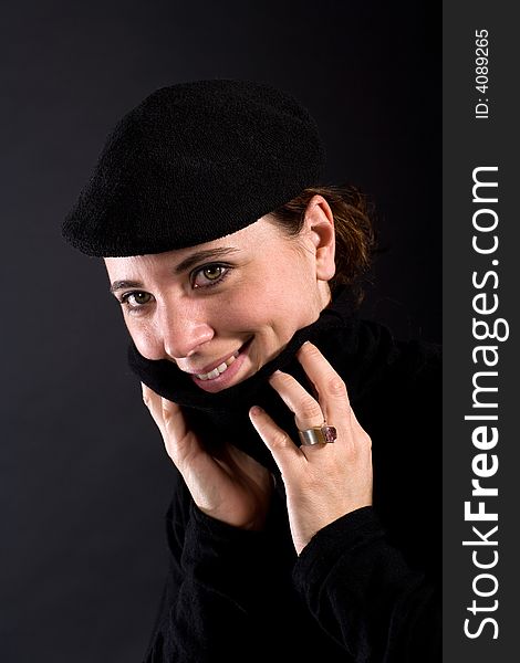 Nice smiling woman with black Pullover and black hat on dark background. Nice smiling woman with black Pullover and black hat on dark background.