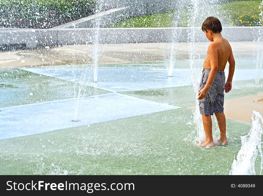 Boy playing in the water fountains. Boy playing in the water fountains