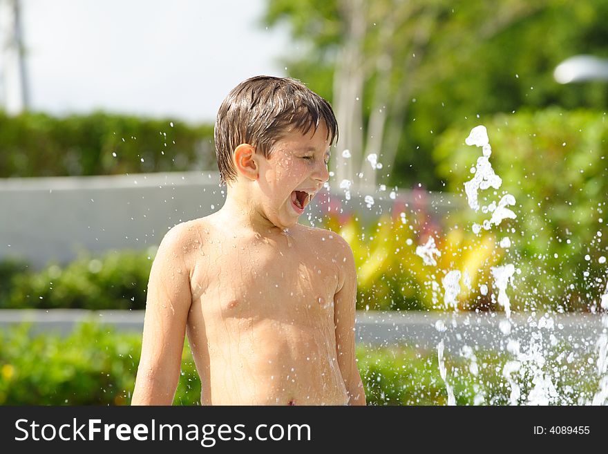 Boy playing in the water fountains and having a great time. Boy playing in the water fountains and having a great time