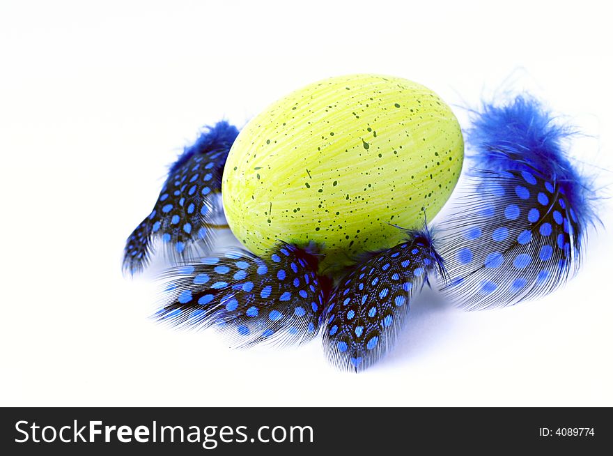Limegreen egg and blue feather on white background. Limegreen egg and blue feather on white background