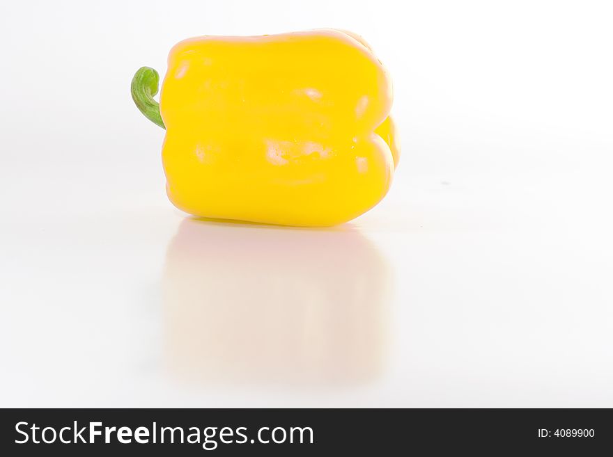 Sweet yellow pepper isolated on white with reflection on glossy surface.