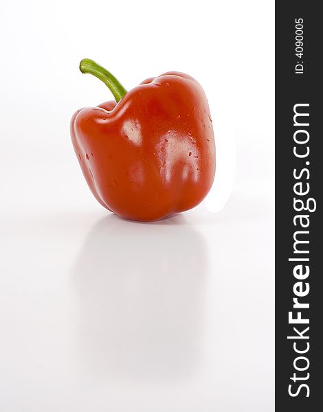 Sweet red pepper isolated on white with reflection on glossy surface.