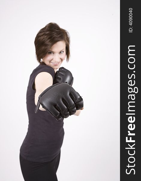 Brunette woman in boxing attire smiling at the camera. Focus is on glove. Brunette woman in boxing attire smiling at the camera. Focus is on glove.