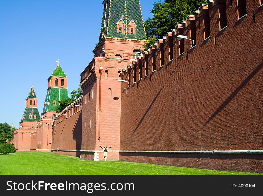 Old Russian outstanding memorial - fortified wall with towers from red brick, detail of Kremlin fortress in Moscow. And small figure of woman. Old Russian outstanding memorial - fortified wall with towers from red brick, detail of Kremlin fortress in Moscow. And small figure of woman.