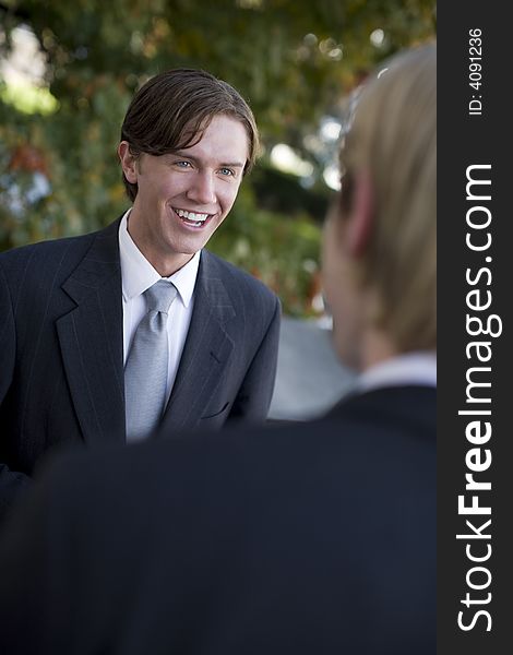 Over shoulder view of businessman standing in suit and tie talking. Over shoulder view of businessman standing in suit and tie talking