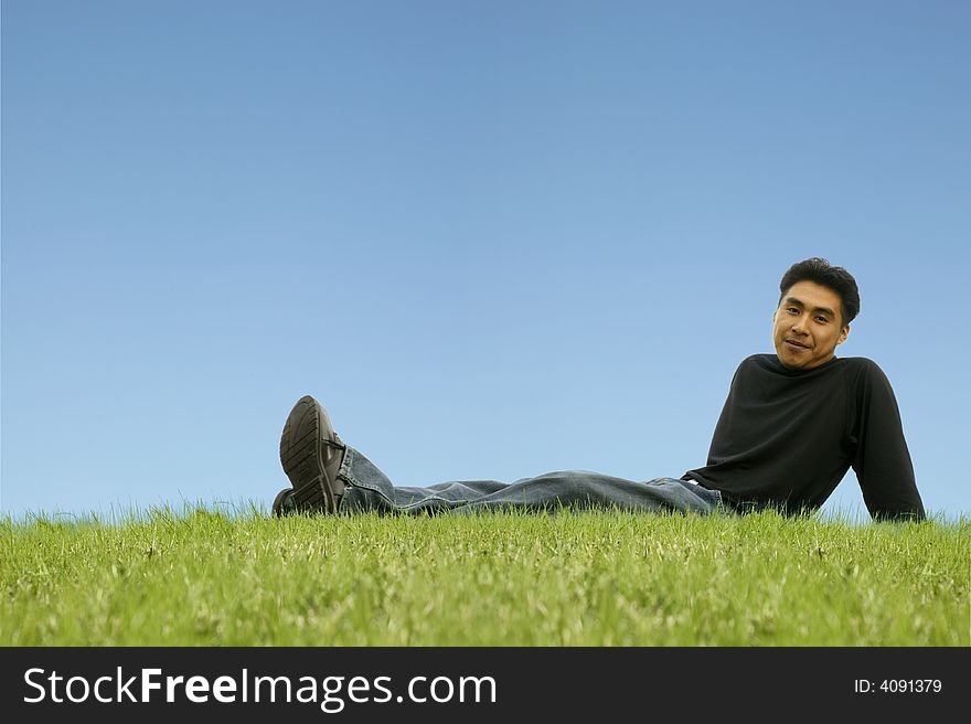 A man sitting and relaxing on grass. with copyspace. A man sitting and relaxing on grass. with copyspace
