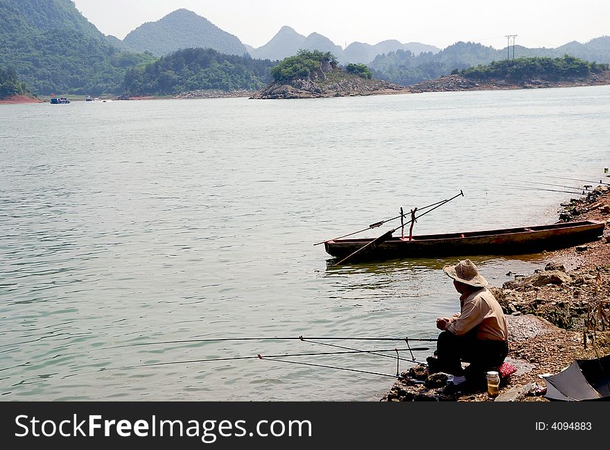 In hongfeng reservoir, Guiyang, GUizhou,  a person fishing there with beatiful water, mountain, so leisure!