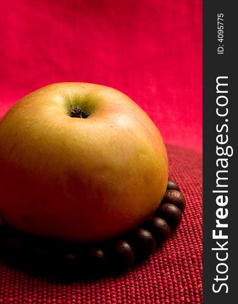 Single apple red background prayer beads macro. Single apple red background prayer beads macro