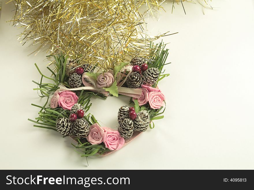 Gold and silver tinsel with heart shaped wreath and silver bells christmas tree decorations over a light background. Gold and silver tinsel with heart shaped wreath and silver bells christmas tree decorations over a light background