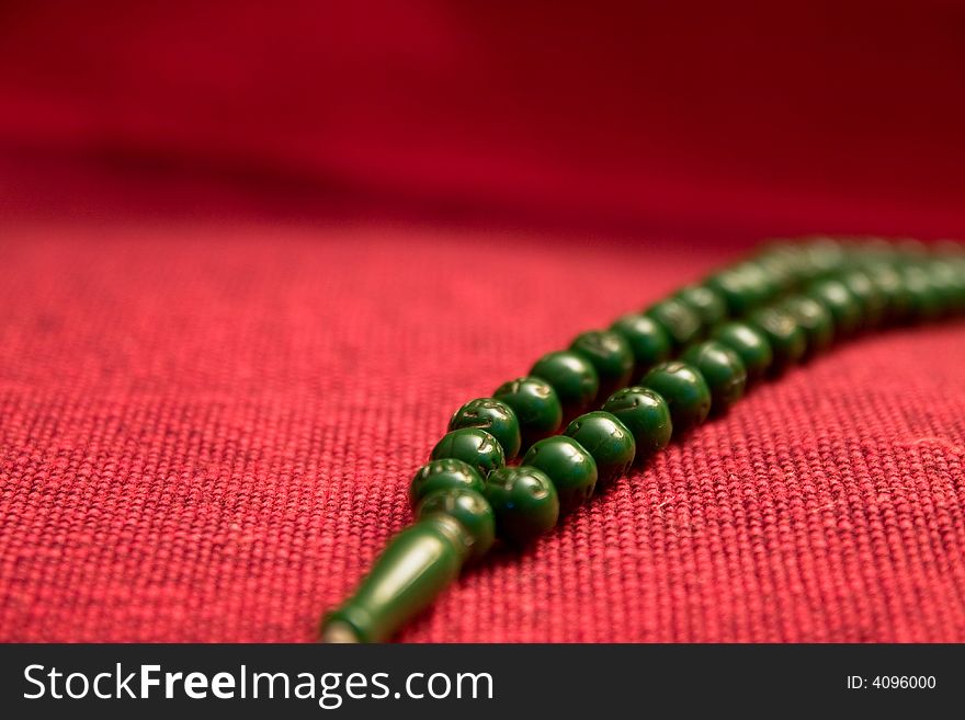 Green prayer beads in red background macro details